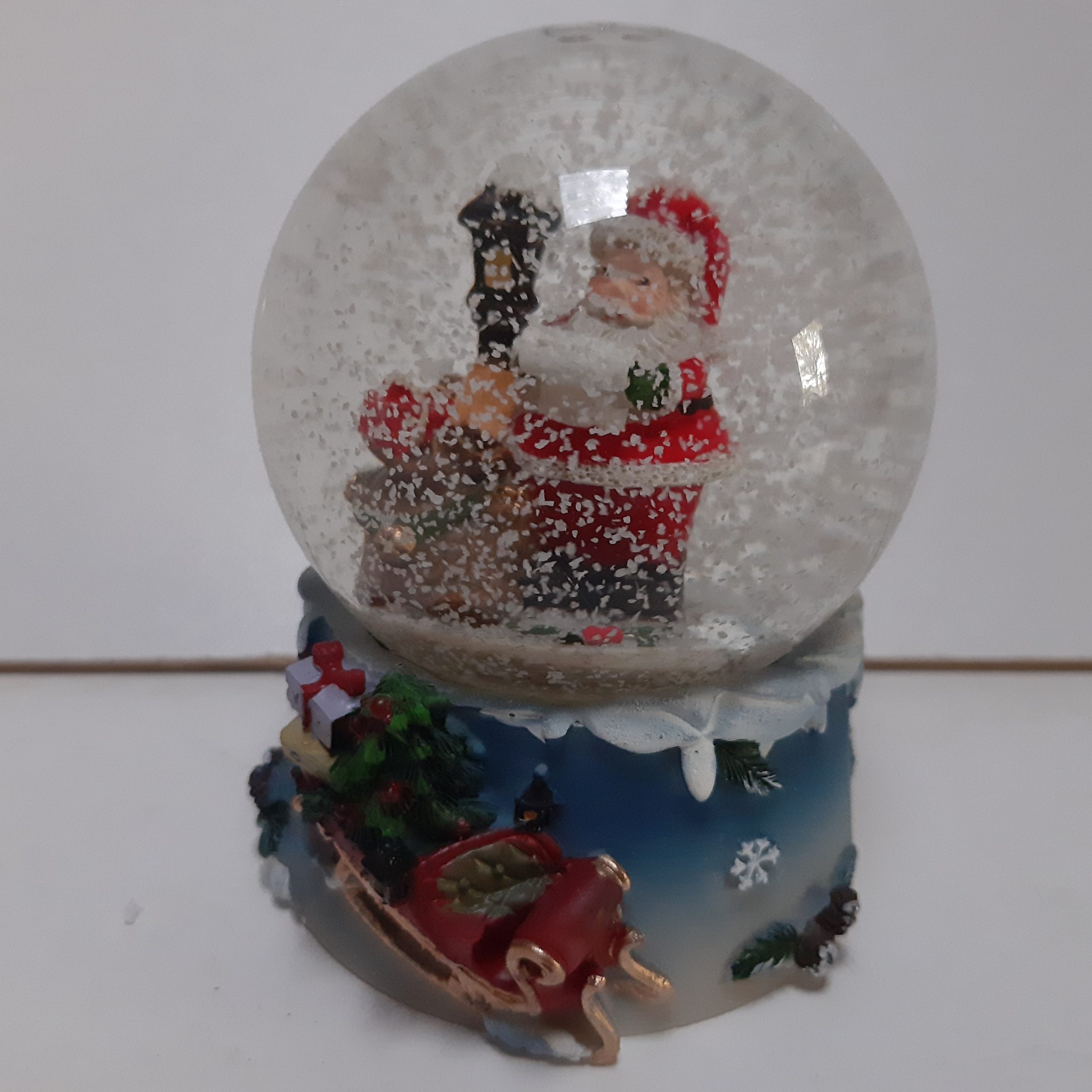 Sneeuwbol kerstman met zak cadeaus bij lantaarn op blauwe basis met arrenslee 9cm hoog